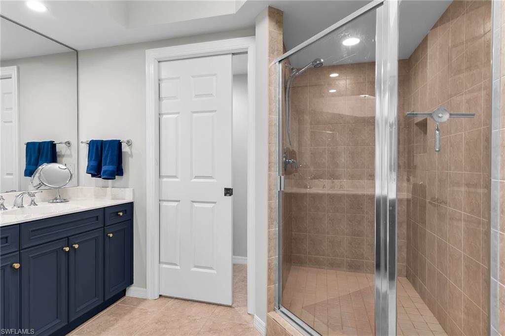1065 Borghese Lane, Unit 1003 Naples, FL 34114 - Photo 18 of 35 a bathroom with a granite countertop sink mirror and shower