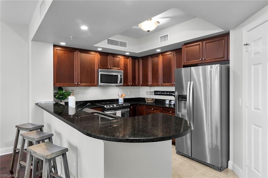 1065 Borghese Lane, Unit 1003 Naples, FL 34114 - Photo 5 of 35 a kitchen with stainless steel appliances granite countertop a sink a stove a microwave and a refrigerator