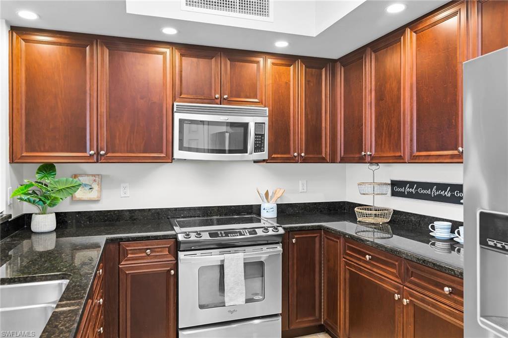 1065 Borghese Lane, Unit 1003 Naples, FL 34114 - Photo 6 of 35 a kitchen with wooden cabinets and a stove top oven