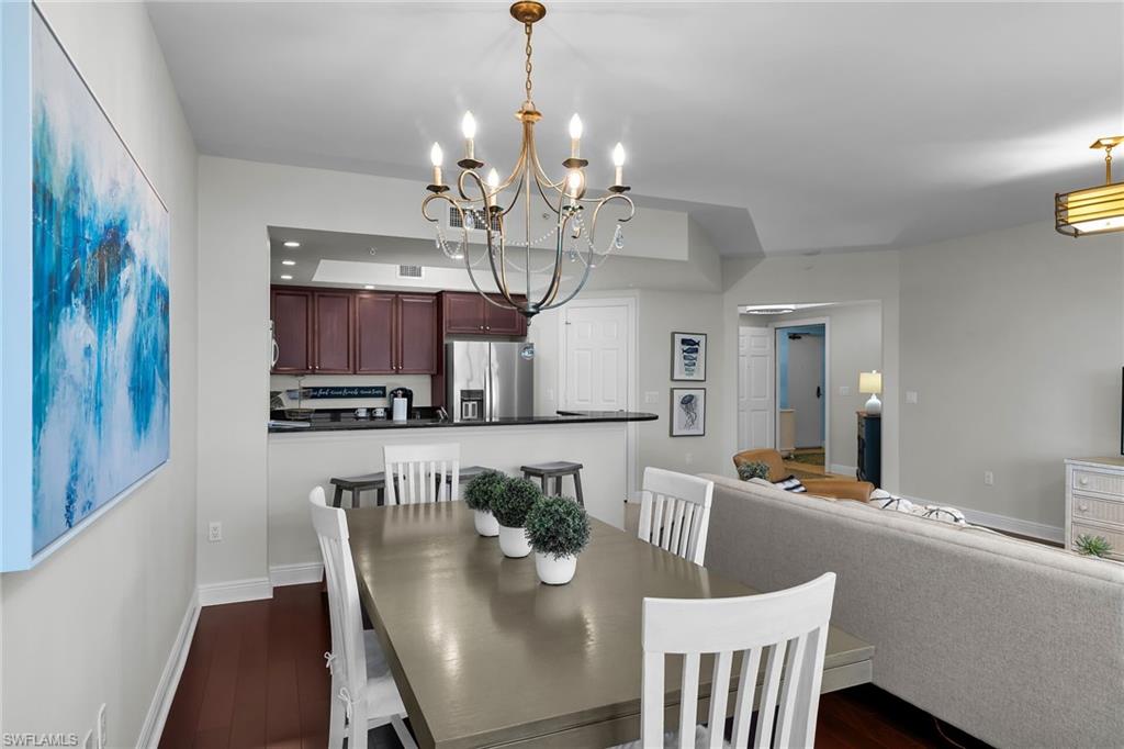 1065 Borghese Lane, Unit 1003 Naples, FL 34114 - Photo 9 of 35 a view of a dining room with furniture a chandelier and wooden floor