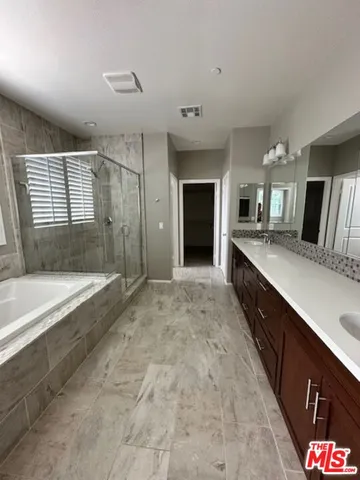 a spacious bathroom with a granite countertop tub sink shower and mirror