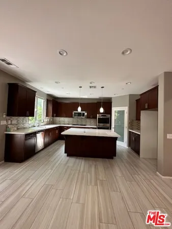 a large kitchen with stainless steel appliances a large counter top and wooden floors