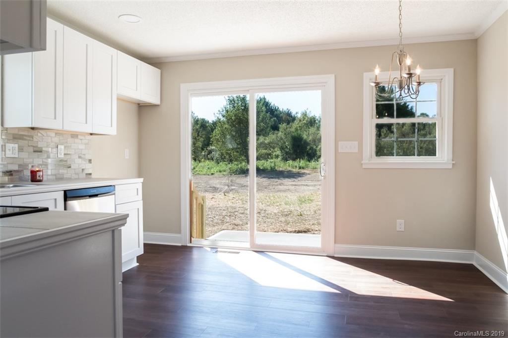 839 Sikes Mill Road Monroe, NC 28110 - Photo 14 of 26 a kitchen with wooden floors and white cabinets