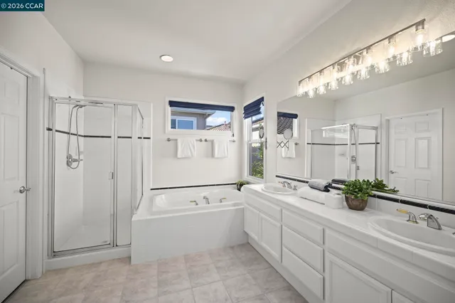 a spacious bathroom with a double vanity sink a mirror a bathtub and a shower