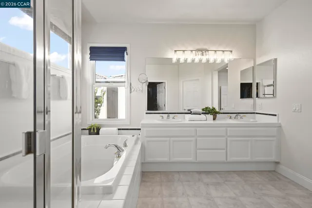 a spacious bathroom with a double vanity sink a large mirror and shower