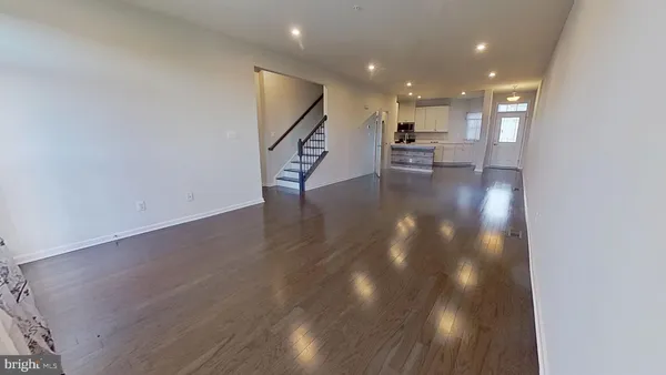 a view of a hallway with wooden floor and a kitchen space