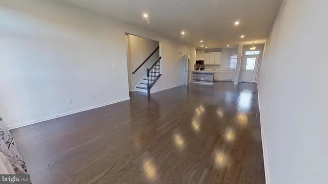 a view of a hallway with wooden floor and a kitchen space