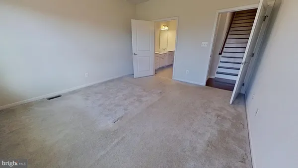 a view of an empty room with wooden floor and stairs