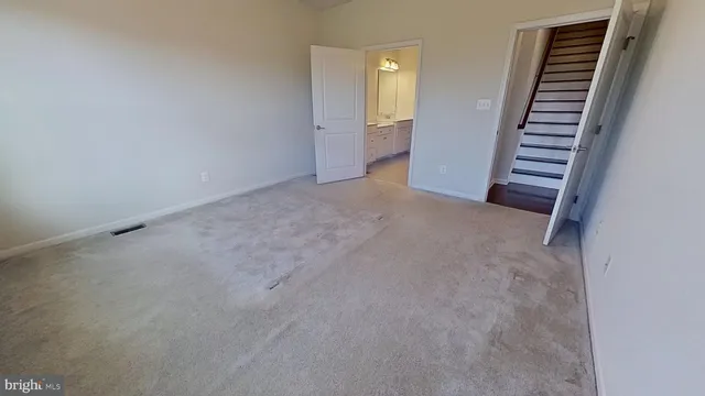 a view of an empty room with wooden floor and stairs