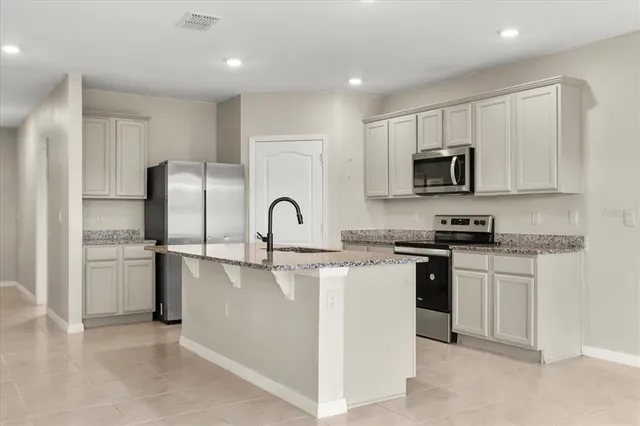 a kitchen with stainless steel appliances granite countertop a refrigerator and a stove top oven