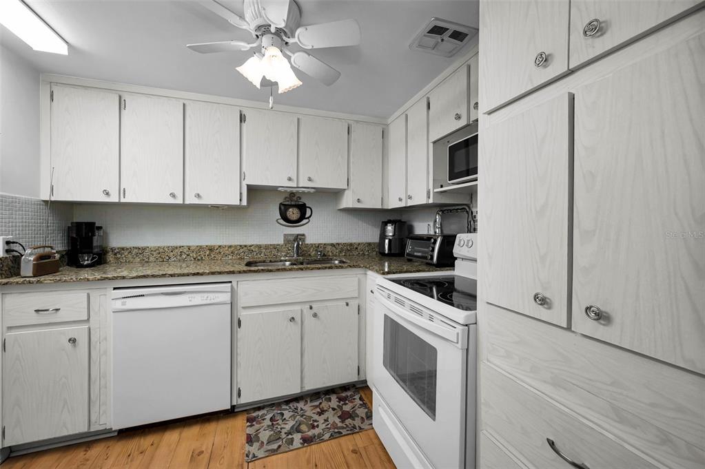 2043 Denmark Street, Unit 39 Clearwater, FL 33763 - Photo 9 of 37 a kitchen with stainless steel appliances granite countertop white cabinets a sink a stove a refrigerator and white cabinets