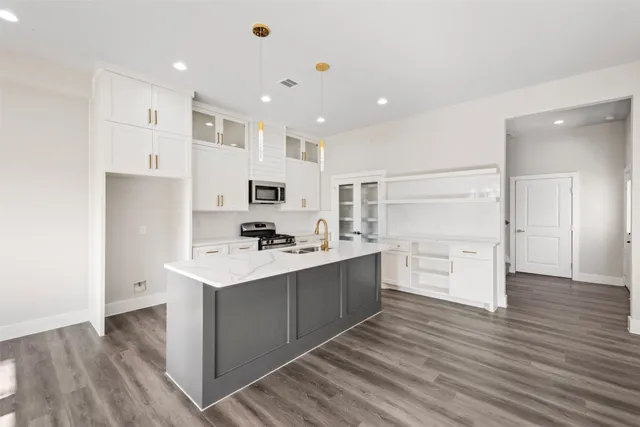 a kitchen with stainless steel appliances a sink a stove a refrigerator cabinets and wooden floor