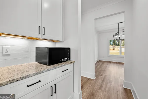 a kitchen with granite countertop white cabinets and a wooden floor