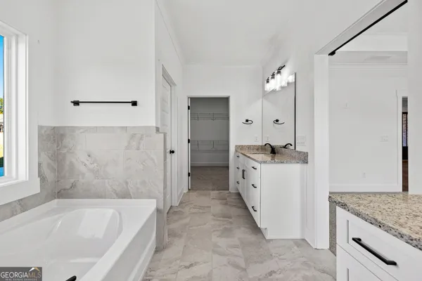 a bathroom with a granite countertop sink a mirror and a bathtub