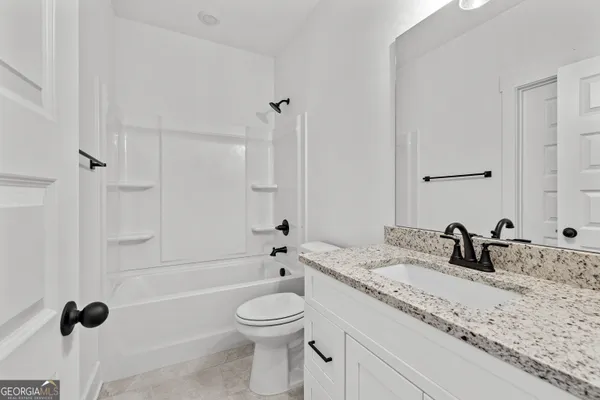 a bathroom with a granite countertop sink a toilet and a tub