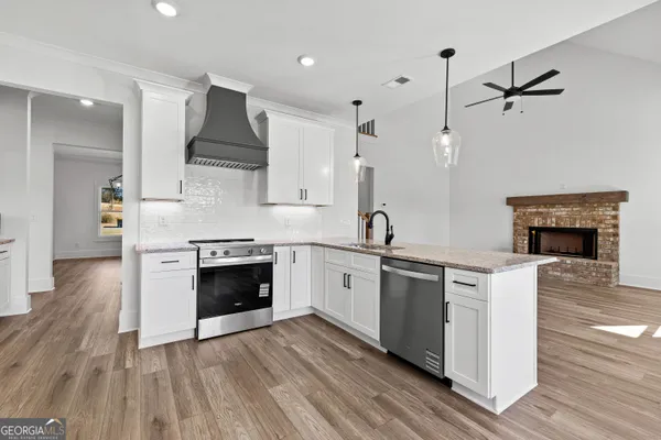 a kitchen with stainless steel appliances granite countertop a stove top oven a sink and a refrigerator