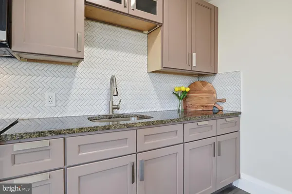 a kitchen with granite countertop white cabinets and a sink