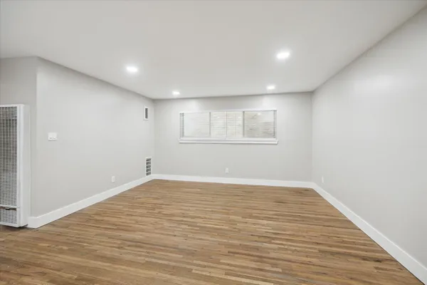 a view of an empty room with wooden floor and a window