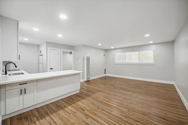 a large white kitchen with kitchen island a sink wooden floor and white stainless steel appliances