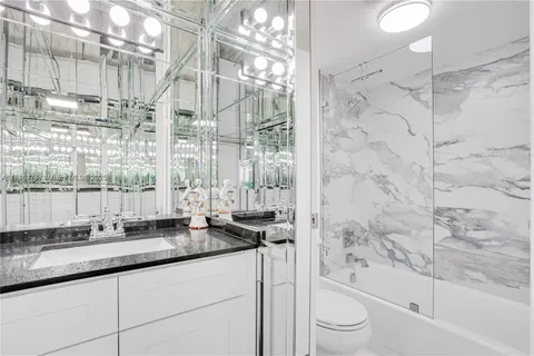 a bathroom with a granite countertop sink a toilet and bathtub