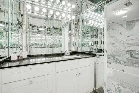 a bath room with granite countertop a sink and a shower