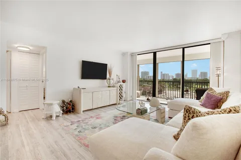 a living room with furniture a flat screen tv and a floor to ceiling window
