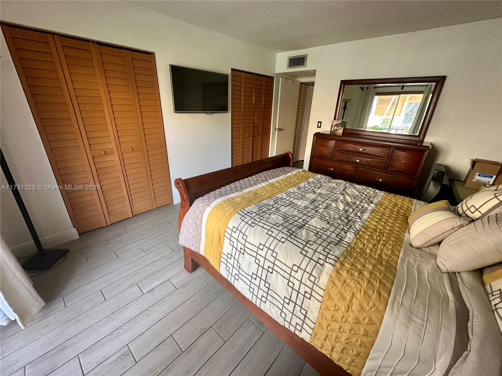 17911 Northwest 68th Avenue, Unit M106 Hialeah, FL 33015 - Photo 19 of 43 a bedroom with a bed and wooden floor