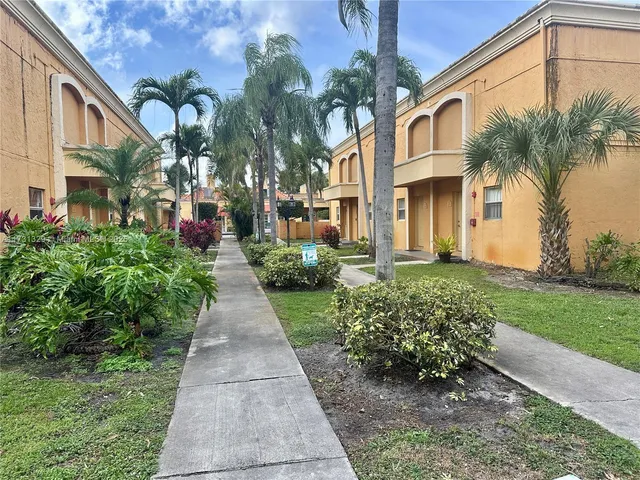a front view of a house with a yard and potted plants