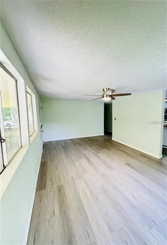 a view of empty room with wooden floor and fan