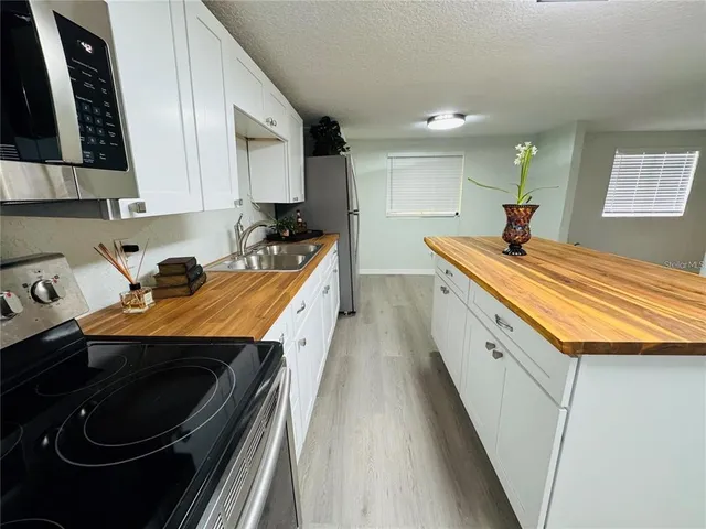 a room with stainless steel appliances granite countertop a sink and cabinets