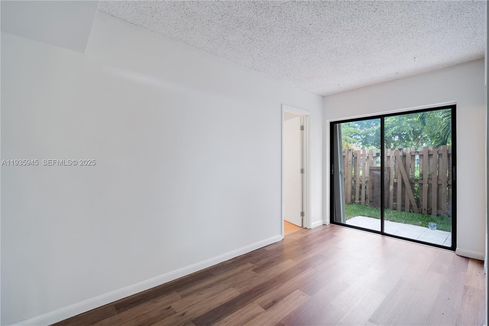 11483 Southwest 109th Road, Unit 2E Miami, FL 33176 - Photo 15 of 45 an empty room with wooden floor and windows
