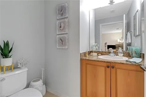 a bathroom with a granite countertop sink a toilet and a mirror