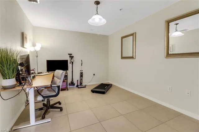 a work room with furniture a potted plant and a lamp