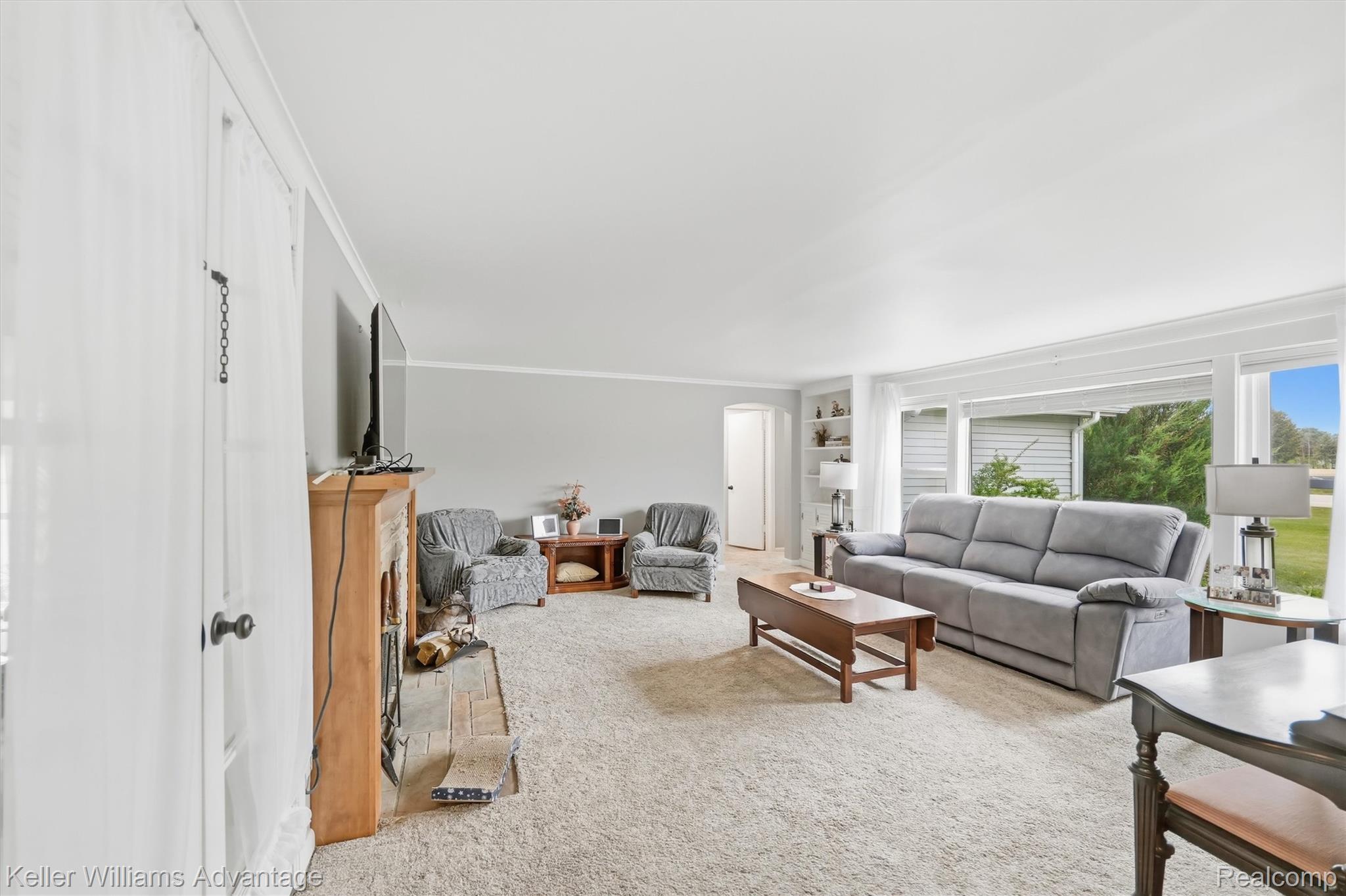 6595 Bray Road Vassar, MI 48768 - Photo 12 of 64 Living area with built in features, light carpet, ornamental molding, and a fireplace