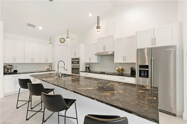 a kitchen with kitchen island a counter top space a sink stainless steel appliances and cabinets