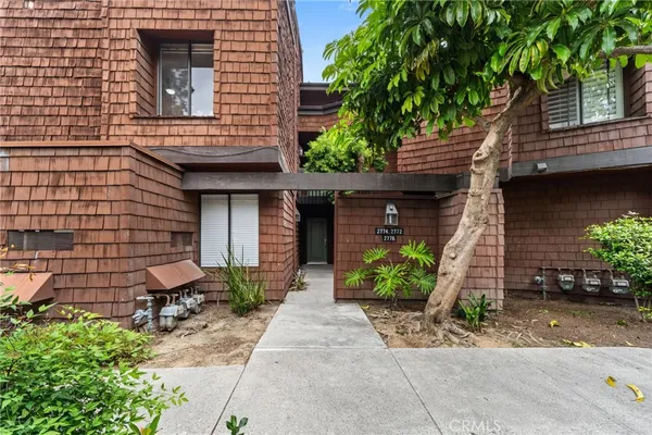 a view of a brick house with plants and a bench