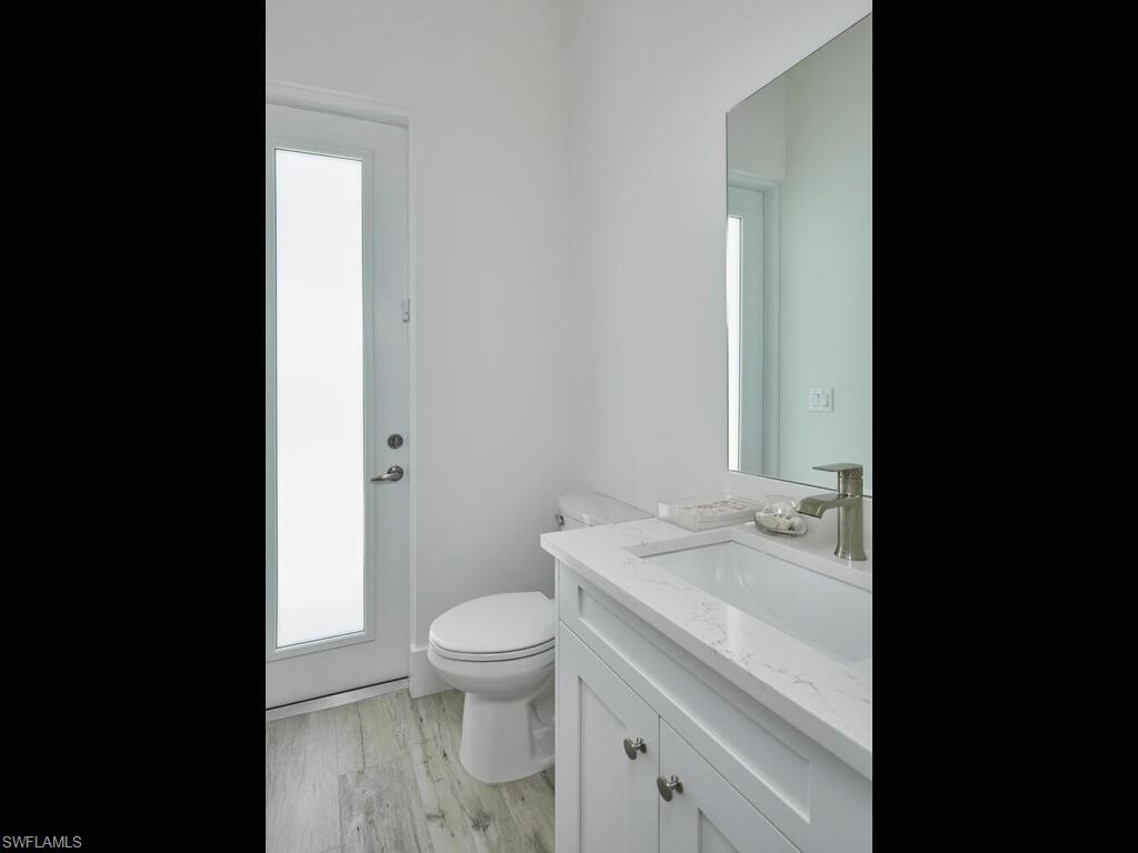 1448 10th Street North Naples, FL 34102 - Photo 14 of 18 a bathroom with a granite countertop toilet a sink and a mirror
