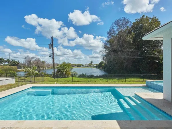 a view of a swimming pool with a yard and a large tree