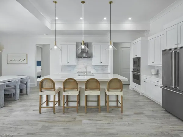 a kitchen with stainless steel appliances granite countertop a dining table chairs refrigerator and sink