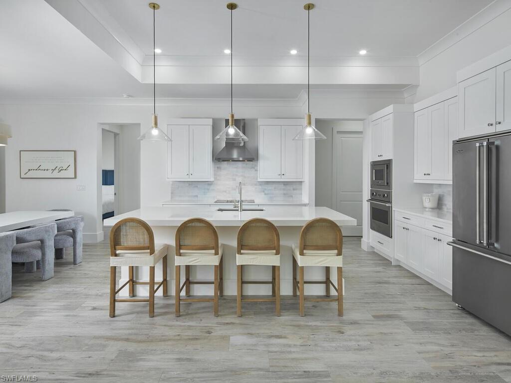 1448 10th Street North Naples, FL 34102 - Photo 4 of 18 a kitchen with stainless steel appliances granite countertop a dining table chairs refrigerator and sink