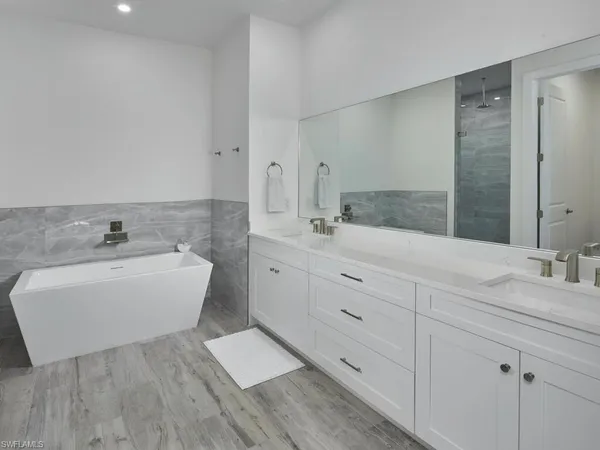 a bathroom with a double vanity sink a mirror and bathtub