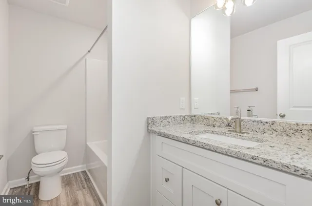 a bathroom with a granite countertop sink toilet and mirror
