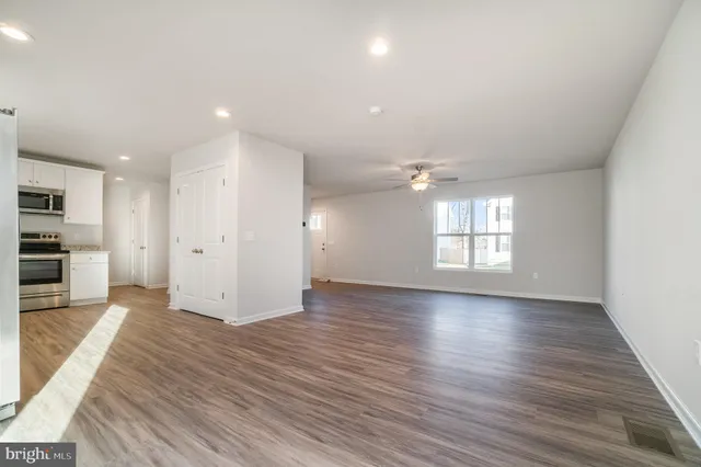 an empty room with wooden floor cabinet and windows