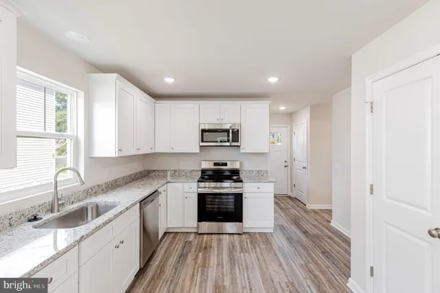 a kitchen with granite countertop stainless steel appliances a sink and cabinets