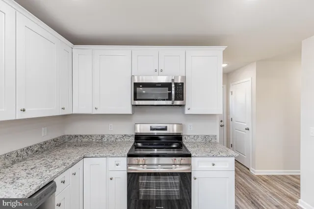 a kitchen with granite countertop white cabinets and stainless steel appliances