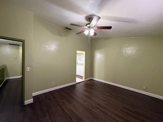 an empty room with wooden floor and a ceiling fan