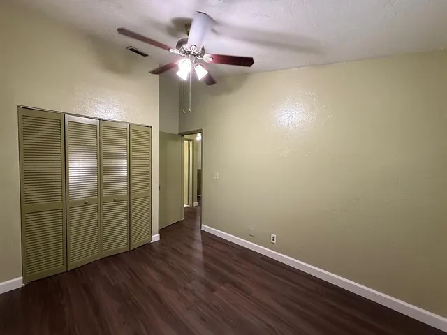 an empty room with wooden floor and fan