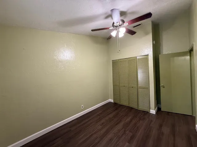 an empty room with wooden floor and ceiling fan