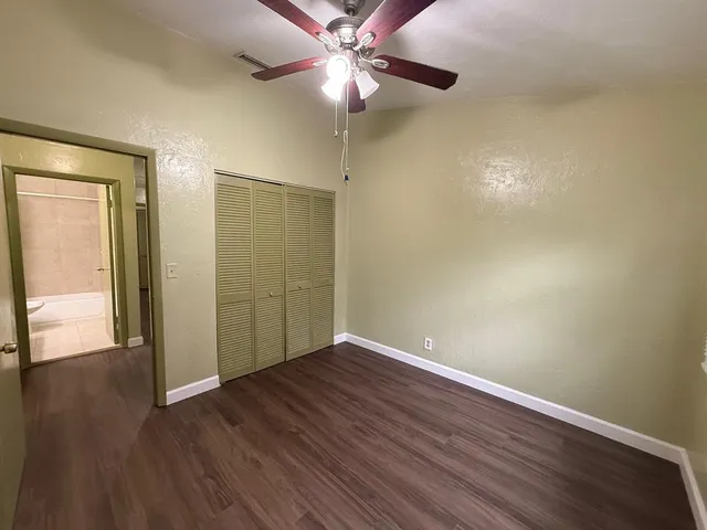 an empty room with wooden floor fan and window