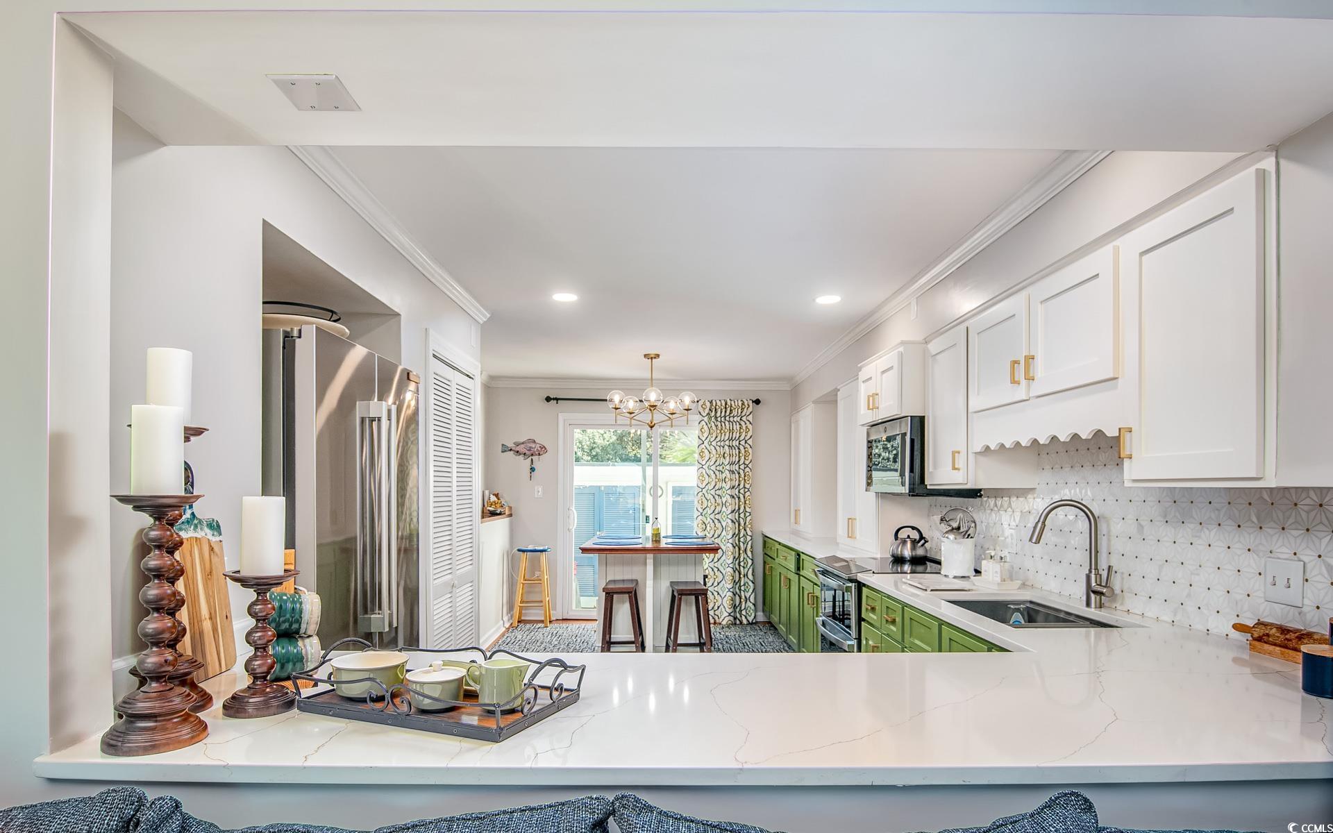 27 Pheasant Loop, Unit 293 Georgetown, SC 29440 - Photo 7 of 23 Kitchen featuring white cabinets, ornamental molding, a chandelier, appliances with stainless steel finishes, and light stone counters